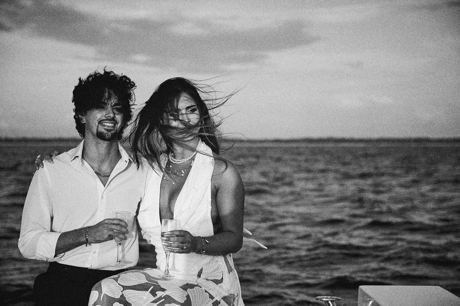 A windswept laugh with champagne at sea, in black and white